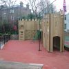 Side view of St Christopher's adventure play area with timber gatehouse firepole and climbing routes
