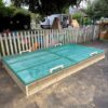 Bespoke timber sandpit with green cover in play area