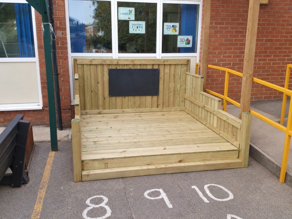 Compact timber chalkboard stage fitted beside a school building and existing railings