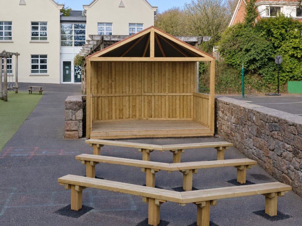 Covered timber stage fitted between existing stone walls with three rows of audience benches