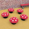 Five red and white mushroom seats on yellow playground surfacing