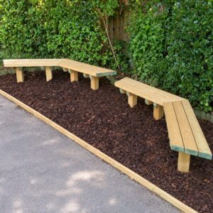 Two groups of angled timber bench seating in a bark bed beside a hedge