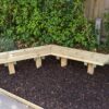 Two timber bench sections joined at an angle beside a hedge