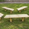 Separate backless timber benches arranged in a group on grass