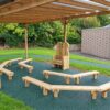 Shaped timber storytelling chair with angled benches beneath a playground canopy