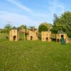 Four linked timber garden play structures with bridges, swings and a green slide